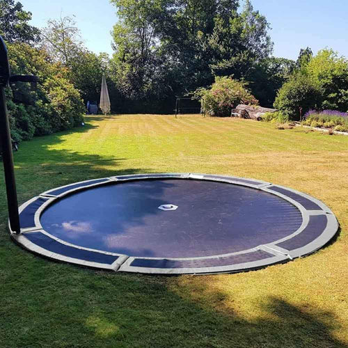 Large sunken trampoline in lawned garden